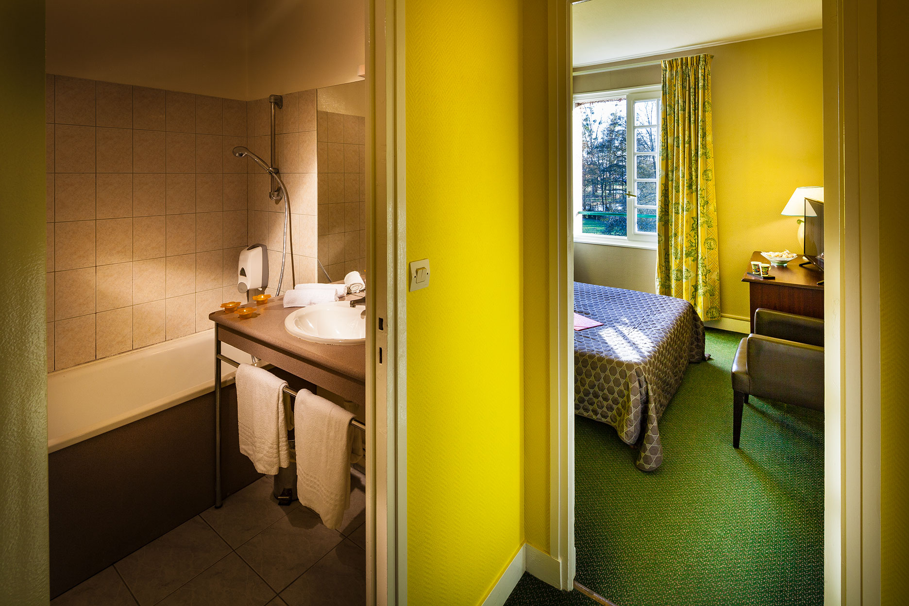 Intérieur de la chambre Citron, bureau, écran, salle de bains avec toilette.